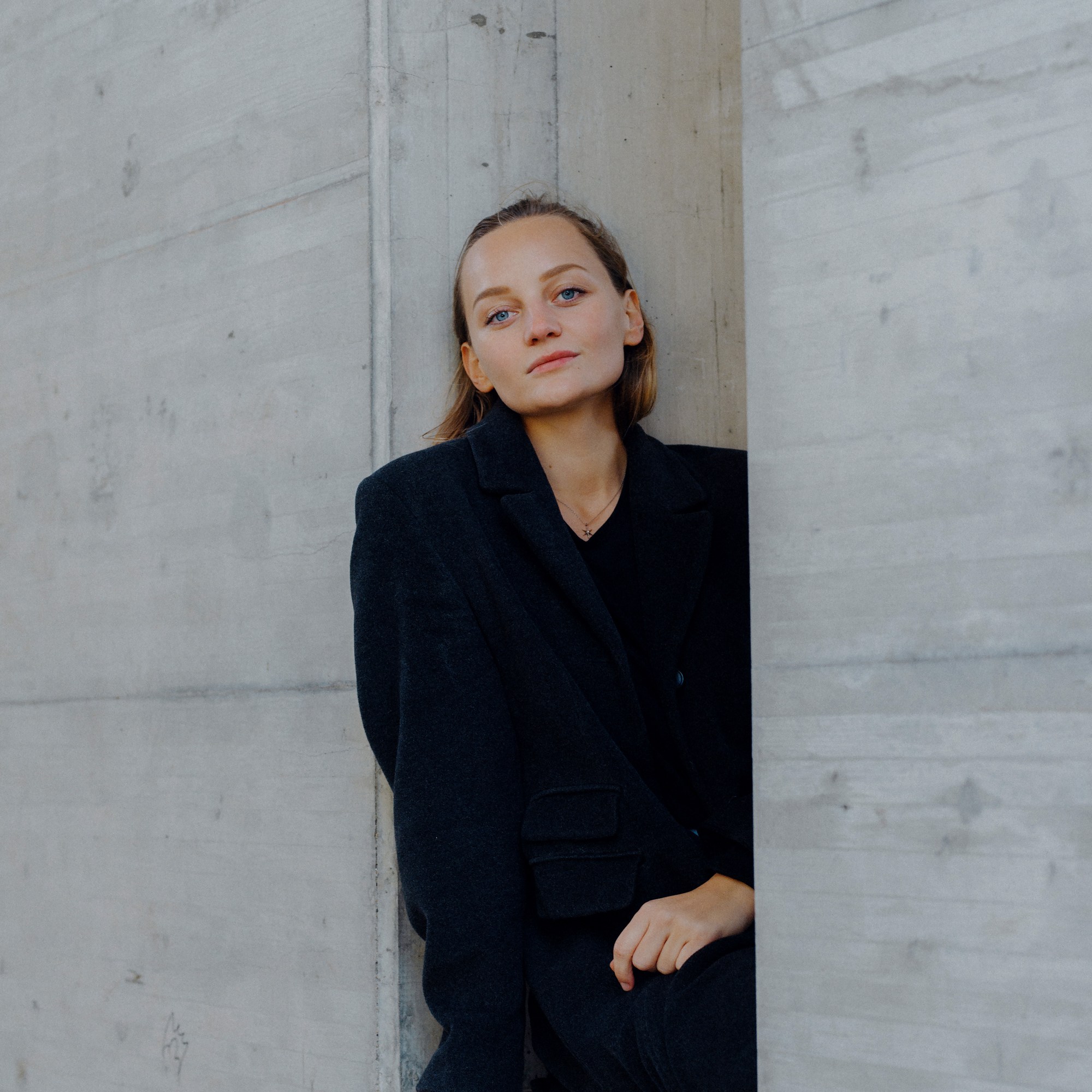 Anna Zöch in graue Steinwand sitzend